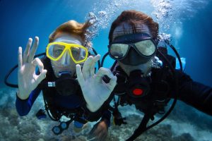 18043078 - underwater shoot of a young couple diving with scuba in a tropical sea and showing ok signal
